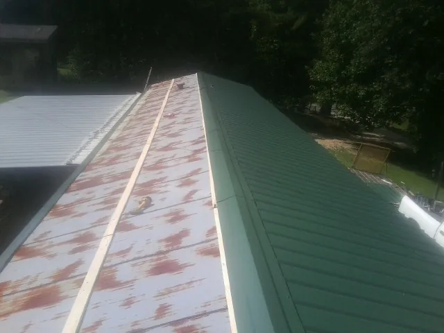 Old rusted panels beside newly installed green metal roofing — Wind Damage Roof Repair by Roofing Brothers in Cedar Hill