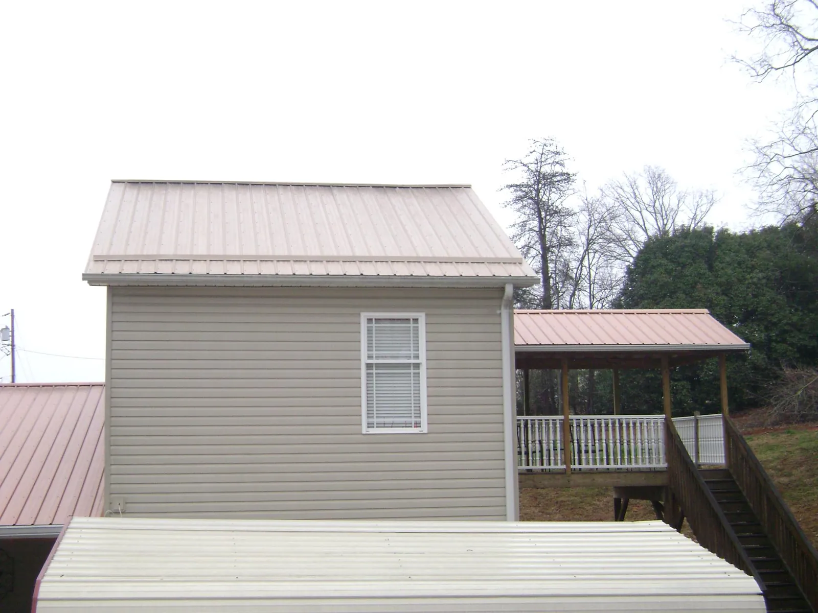 Tan metal roofs on a two story addition and attached porch, from a Roof Replacement job in Cedar Hill